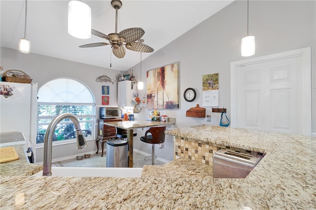 kitchen with stove, ceiling fan, sink, hanging light fixtures, and lofted ceiling