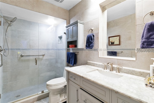 bathroom with vanity, a shower with shower door, tile walls, and toilet