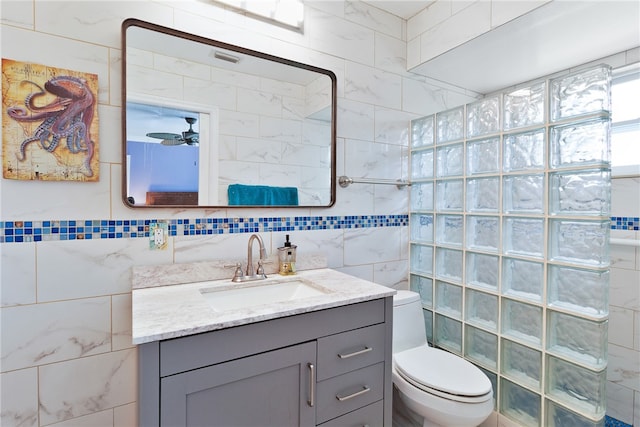 bathroom with a tile shower, vanity, and tile walls