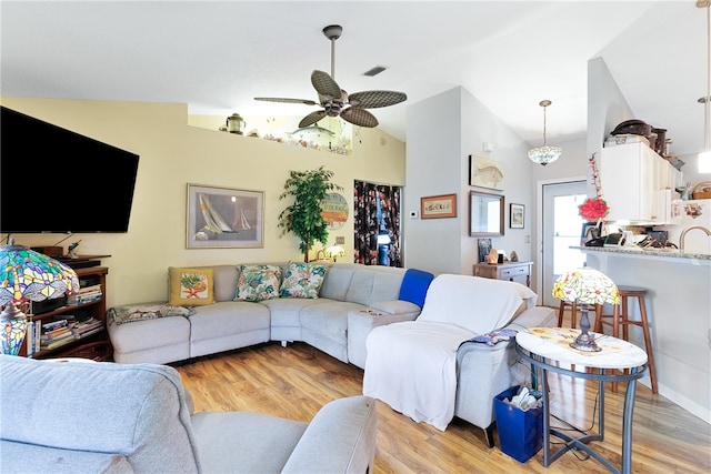 living room with ceiling fan, light hardwood / wood-style floors, and lofted ceiling