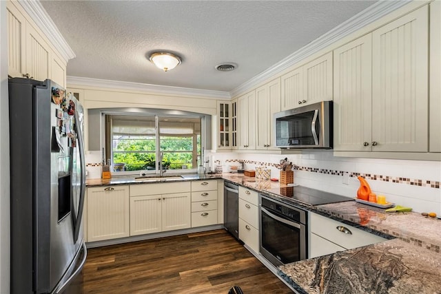 kitchen with dark hardwood / wood-style floors, dark stone countertops, ornamental molding, a textured ceiling, and stainless steel appliances