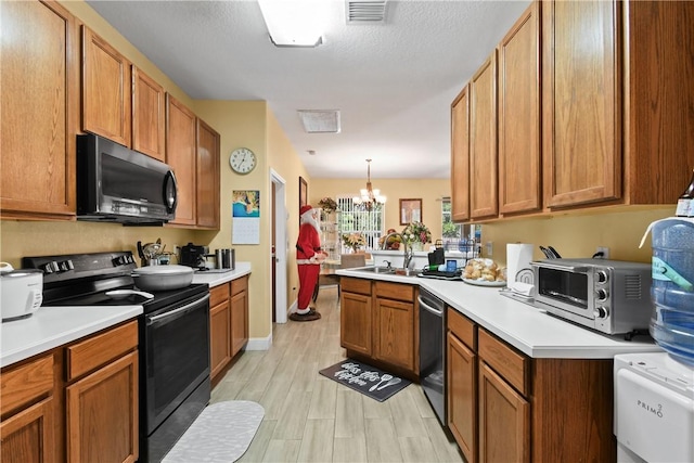 8365 104th Ct, Vero Beach, FL 32967 - kitchen with black appliances, a chandelier, light countertops, light wood-style flooring, and brown cabinets
