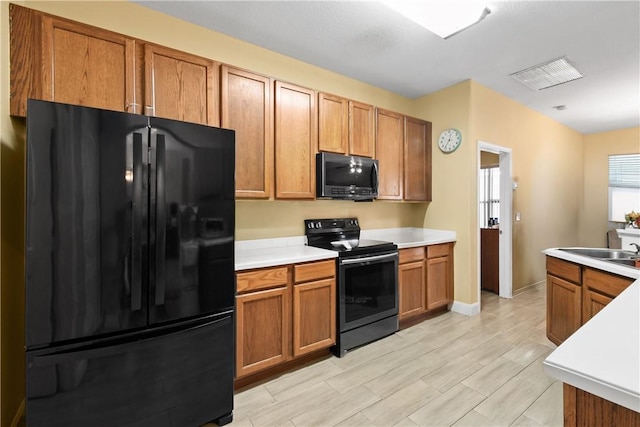 8365 104th Ct, Vero Beach, FL 32967 - kitchen featuring black appliances, light countertops, and brown cabinetry