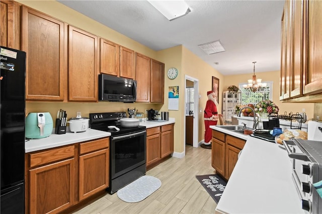 8365 104th Ct, Vero Beach, FL 32967 - kitchen with black appliances, light countertops, a chandelier, light wood finished floors, and hanging light fixtures
