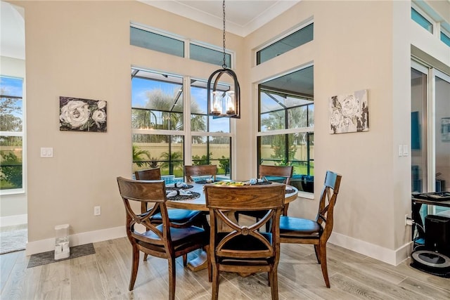 dining space with wood finished floors, plenty of natural light, baseboards, a chandelier, and crown molding