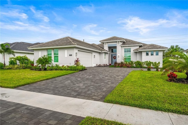 view of front of house featuring a garage, decorative driveway, stucco siding, a front lawn, and a tile roof