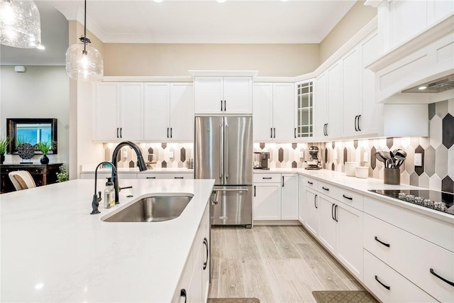 kitchen with high end fridge, a sink, black electric stovetop, and decorative backsplash