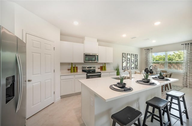502 Saunders St, Sebastian, FL 32958 - kitchen with stainless steel appliances, a breakfast bar, white cabinetry, a center island with sink, and light countertops