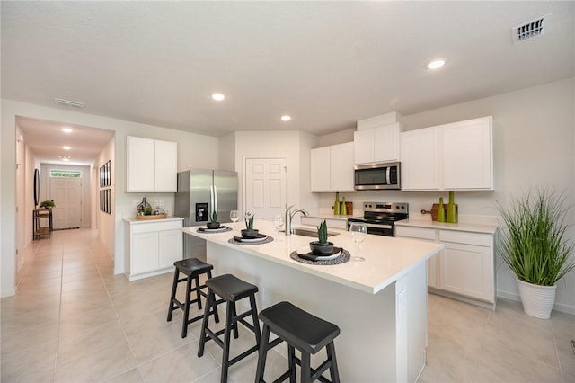 502 Saunders St, Sebastian, FL 32958 - kitchen featuring appliances with stainless steel finishes, a breakfast bar area, light tile patterned flooring, light countertops, and an island with sink