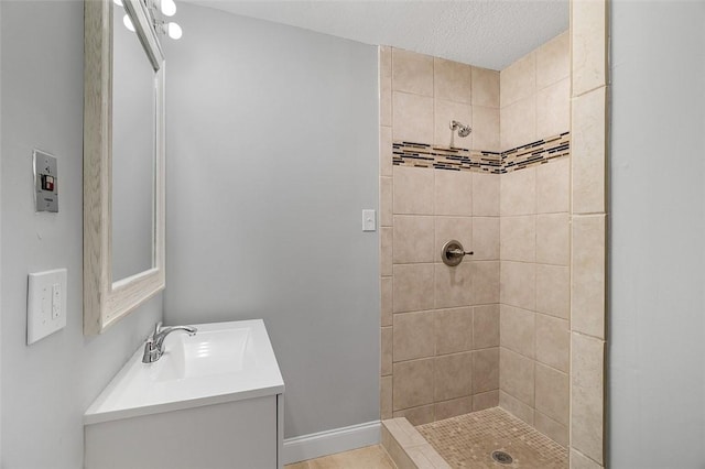 bathroom featuring tiled shower, a textured ceiling, and vanity