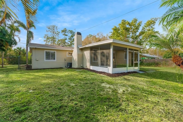 rear view of property featuring a yard, central AC, and a sunroom