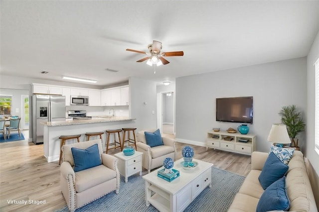 living room with sink, ceiling fan, and light wood-type flooring