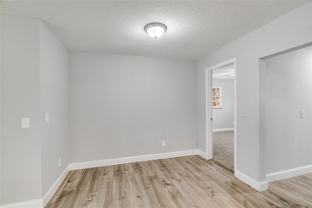 unfurnished room featuring a textured ceiling and light hardwood / wood-style floors