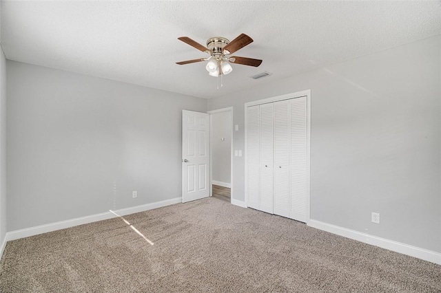 unfurnished bedroom featuring ceiling fan, carpet flooring, a textured ceiling, and a closet