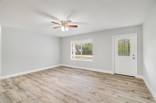 empty room with light hardwood / wood-style floors, ceiling fan, and a textured ceiling