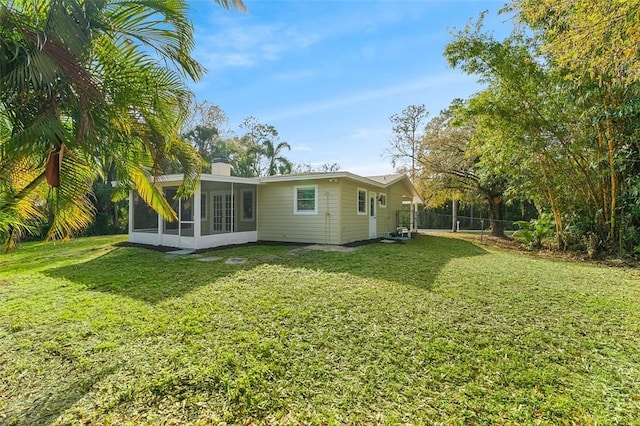 rear view of house with a yard and a sunroom