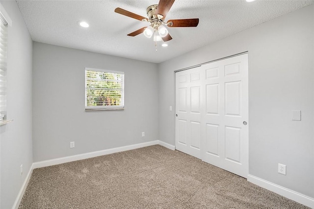 unfurnished bedroom featuring a closet, ceiling fan, carpet floors, and a textured ceiling