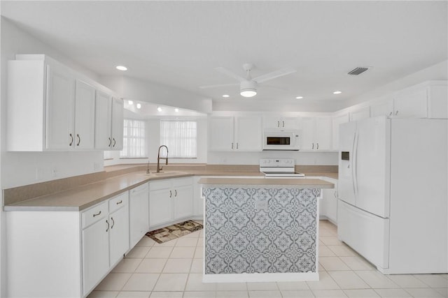 kitchen with ceiling fan, white appliances, a kitchen island, white cabinets, and sink