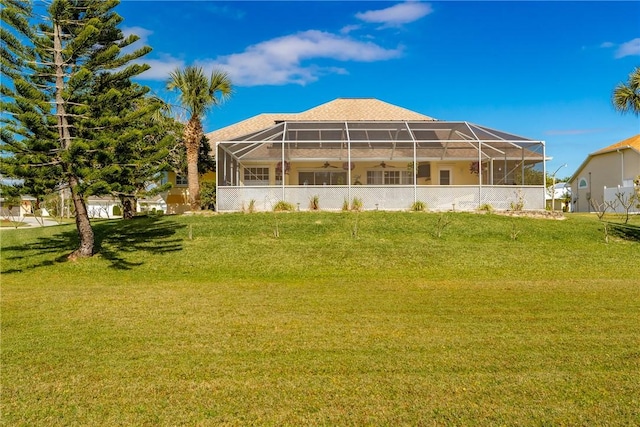 back of property with a lanai and a lawn