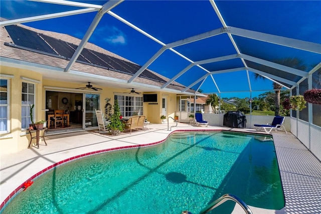 view of swimming pool with ceiling fan, glass enclosure, and a patio