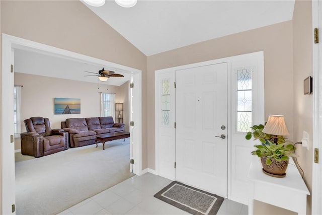 foyer with vaulted ceiling, ceiling fan, and light carpet