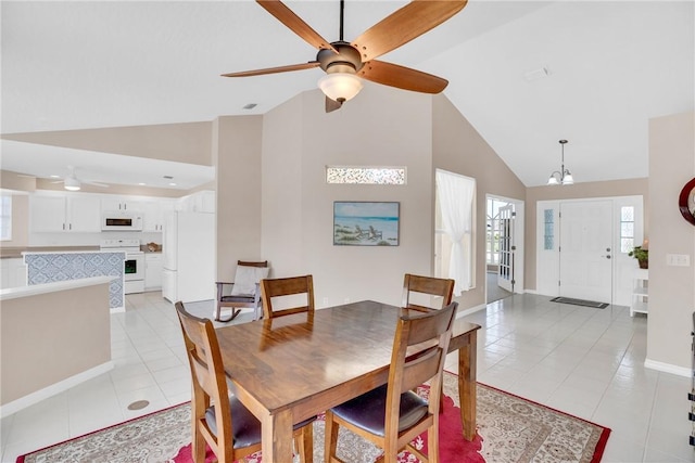 tiled dining room featuring high vaulted ceiling and ceiling fan with notable chandelier