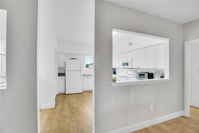 kitchen with white appliances, light hardwood / wood-style flooring, and white cabinets