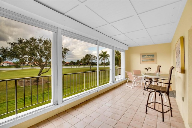 sunroom / solarium featuring a paneled ceiling and a water view