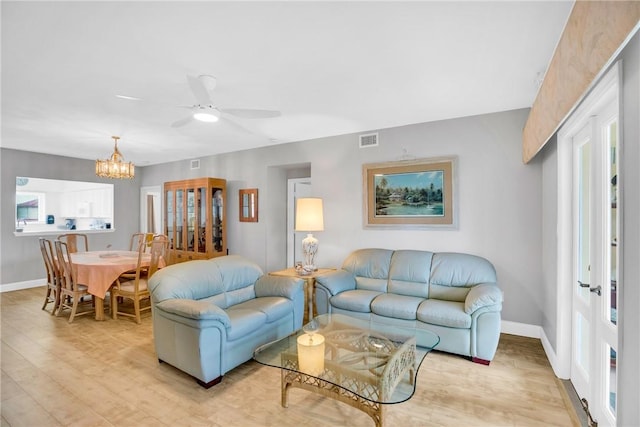 living room with ceiling fan with notable chandelier and light hardwood / wood-style floors