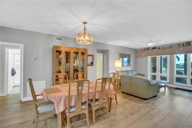 dining room featuring ceiling fan with notable chandelier and light hardwood / wood-style floors