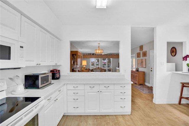 kitchen with white cabinetry, white appliances, light hardwood / wood-style flooring, and a chandelier