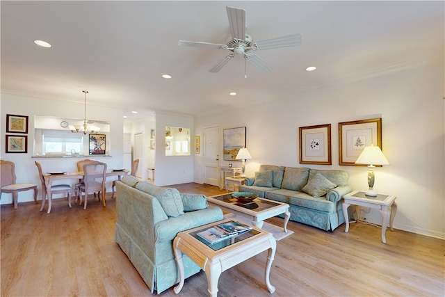 living room featuring ceiling fan with notable chandelier, ornamental molding, and light hardwood / wood-style floors