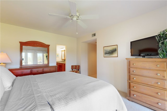 bedroom with ceiling fan, light carpet, and ensuite bathroom