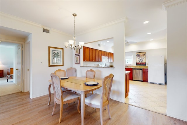 dining space with an inviting chandelier, light wood-type flooring, and ornamental molding