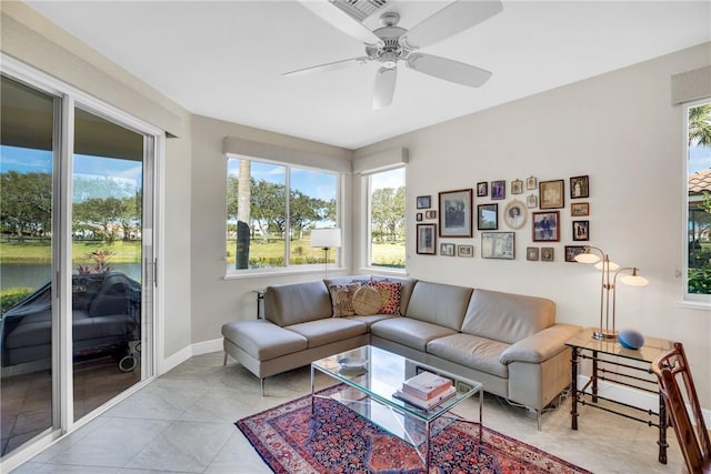 living area featuring a ceiling fan, visible vents, plenty of natural light, and baseboards