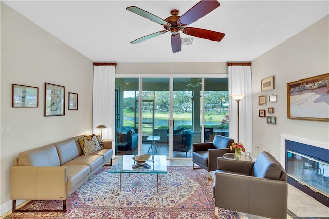 living area featuring a ceiling fan, a glass covered fireplace, and visible vents