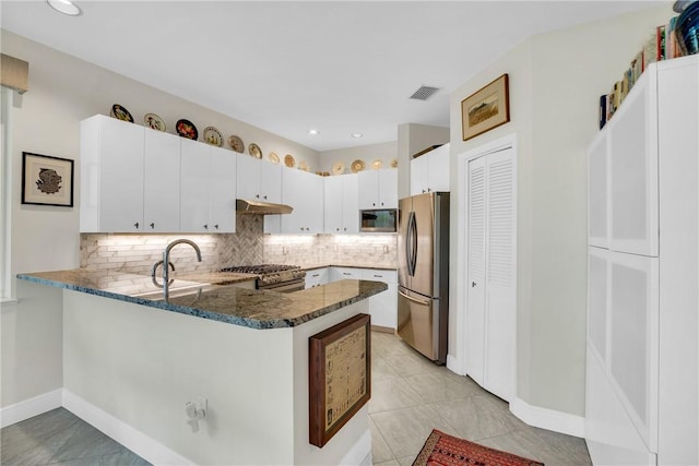 kitchen with visible vents, dark stone counters, a peninsula, stainless steel appliances, and under cabinet range hood