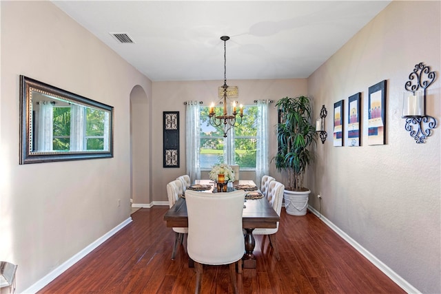 dining area with dark hardwood / wood-style floors and an inviting chandelier