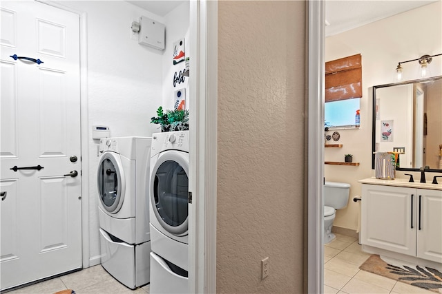 laundry area featuring washing machine and dryer, light tile patterned flooring, and sink