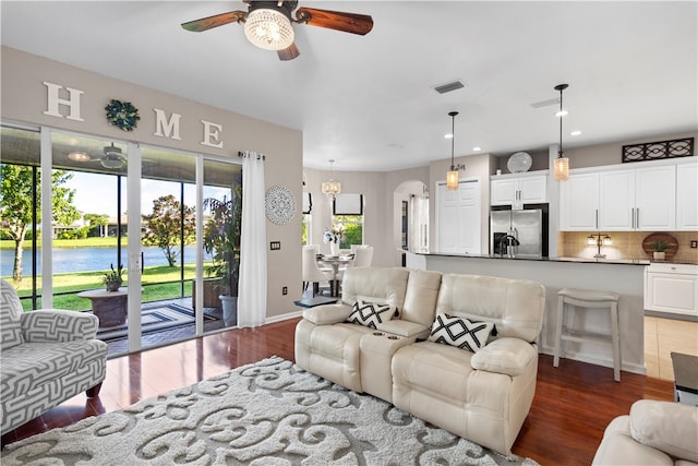 living room with hardwood / wood-style floors, ceiling fan, and a water view