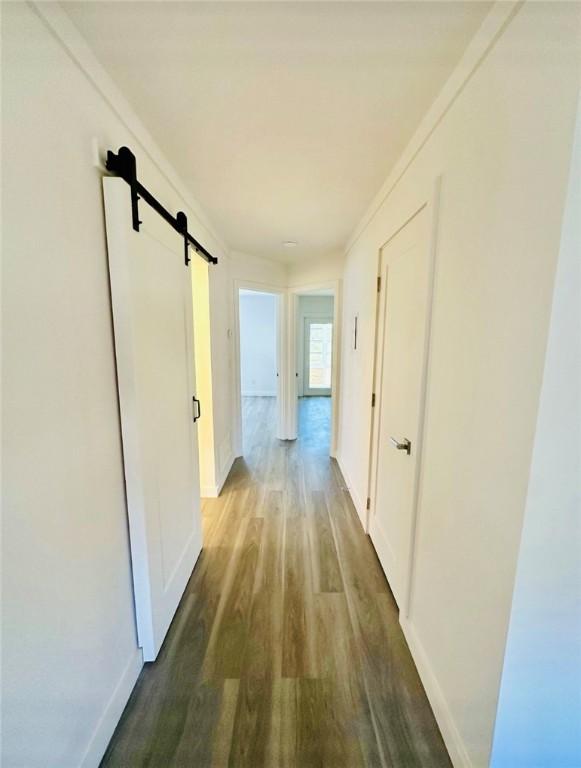 hallway with hardwood / wood-style floors, ornamental molding, and a barn door