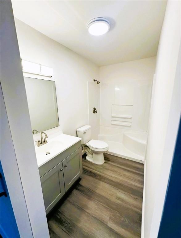 bathroom featuring toilet, a shower, wood-type flooring, and vanity