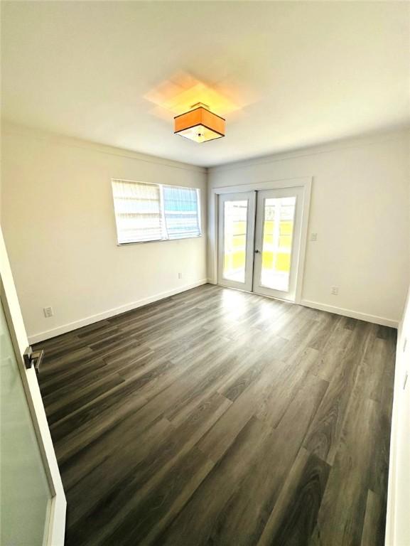 spare room with dark hardwood / wood-style flooring and french doors