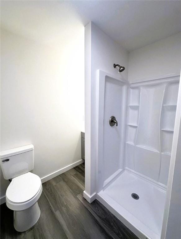 bathroom with toilet, wood-type flooring, and a shower