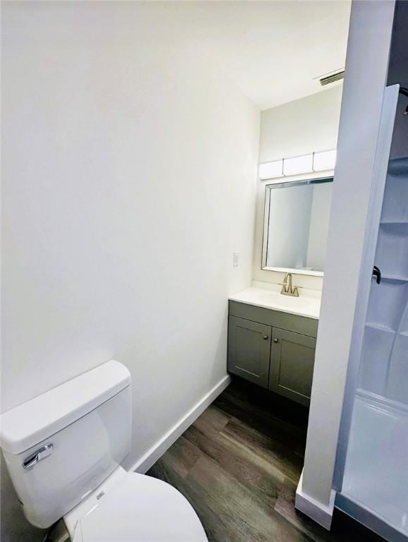 bathroom with hardwood / wood-style flooring, toilet, and vanity