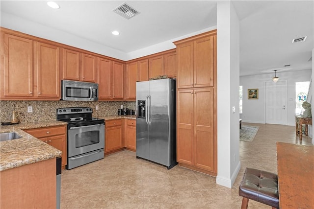 2019 Grey Falcon Cir SW, Vero Beach, FL 32962 - kitchen with appliances with stainless steel finishes, light stone countertops, tasteful backsplash, recessed lighting, and brown cabinets