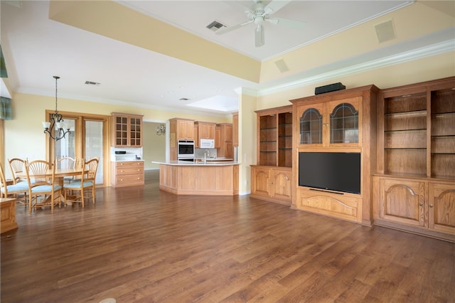 unfurnished living room with sink, ornamental molding, dark hardwood / wood-style floors, ceiling fan with notable chandelier, and a raised ceiling