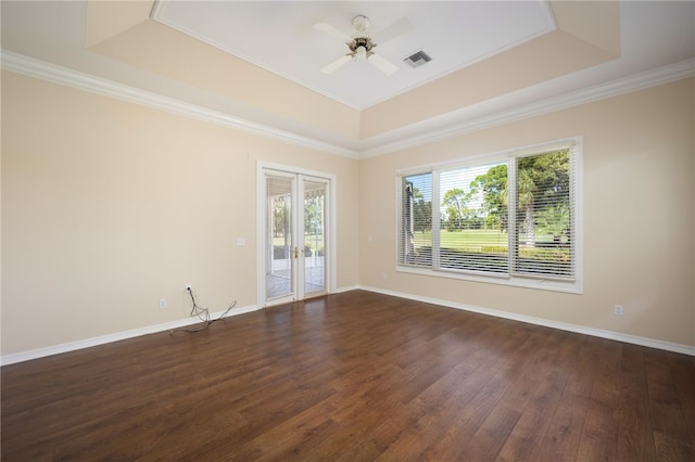 spare room with dark wood-type flooring, ceiling fan, a raised ceiling, and ornamental molding