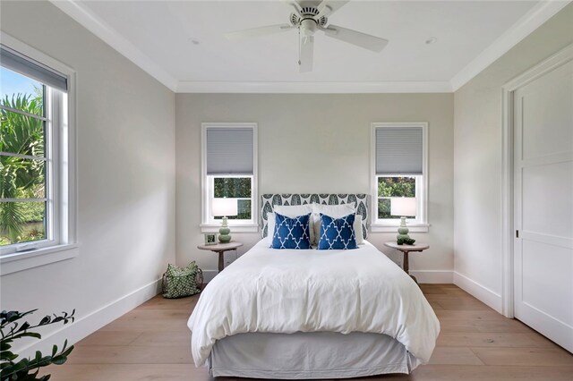 bedroom with ornamental molding, light wood-type flooring, multiple windows, and ceiling fan