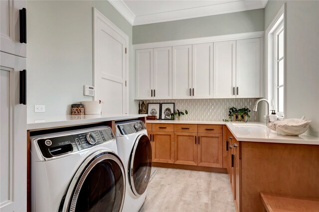 laundry area featuring light hardwood / wood-style floors, cabinets, sink, ornamental molding, and washer and dryer